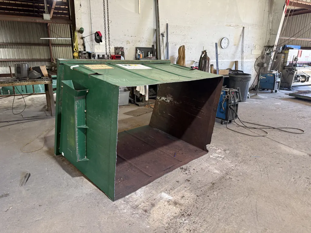 Before: front-load dumpster on its side with the rusted-out floor cut away for floor replacement at North Florida Container in Ocala