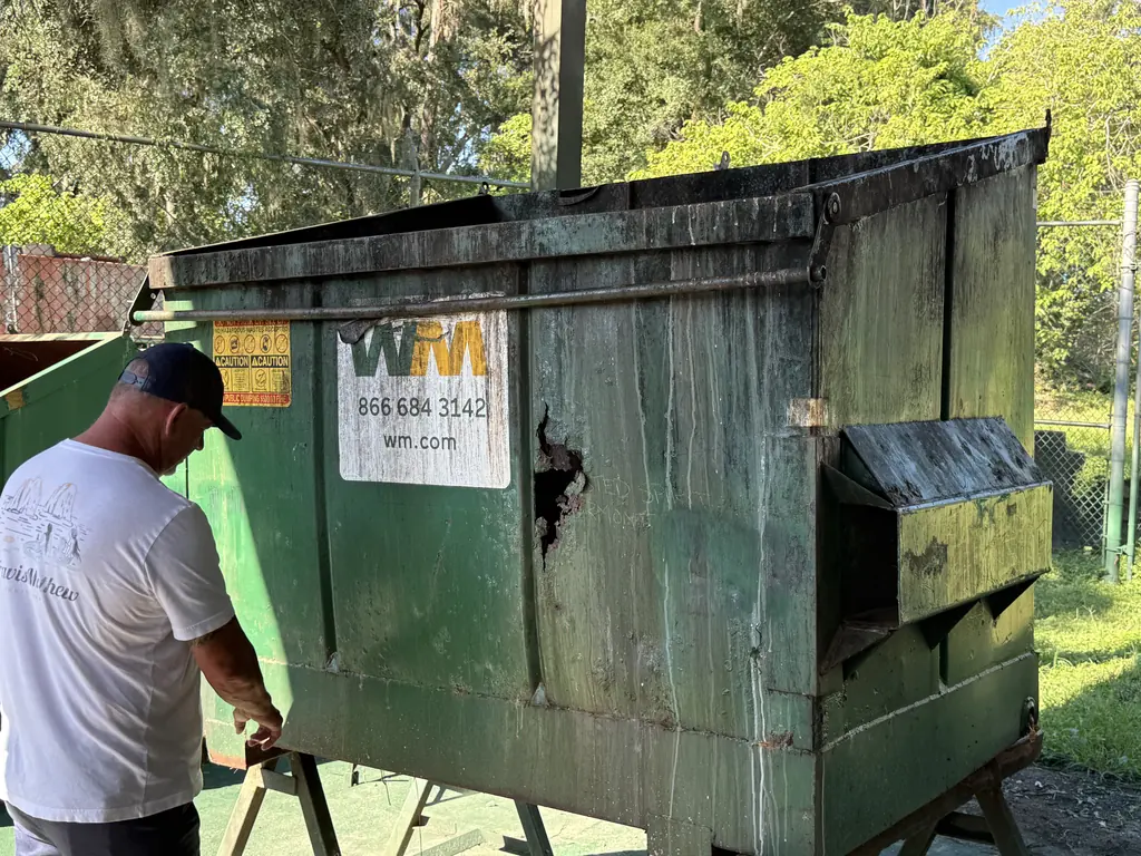 Before: front-load dumpster with a rusted-through side wall arriving for dumpster repair at North Florida Container in Ocala FL