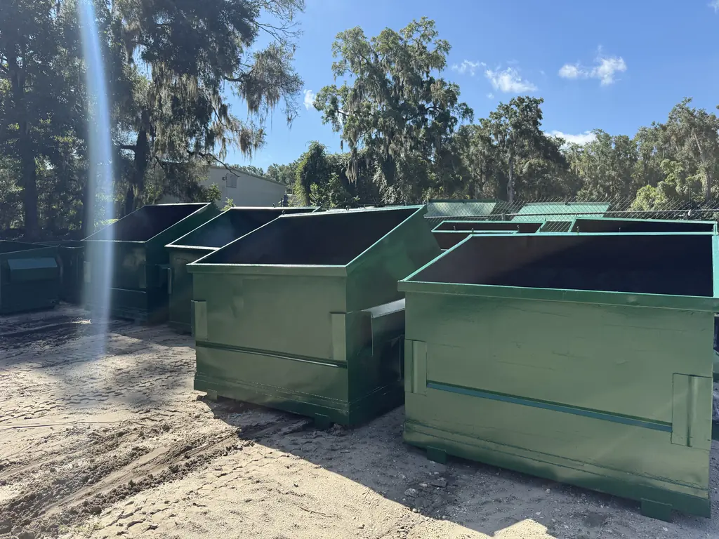 Repaired and repainted front-load dumpsters staged for delivery back to the customer from the Ocala shop
