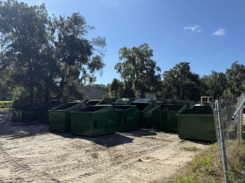 Row of front-load dumpsters rebuilt and repainted at North Florida Container in Ocala, lined up and ready to go back on the route