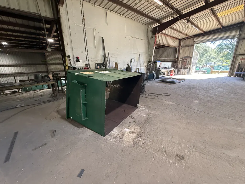 Front-load dumpster tipped on its side showing the rusted floor before dumpster floor repair at NFC in Ocala