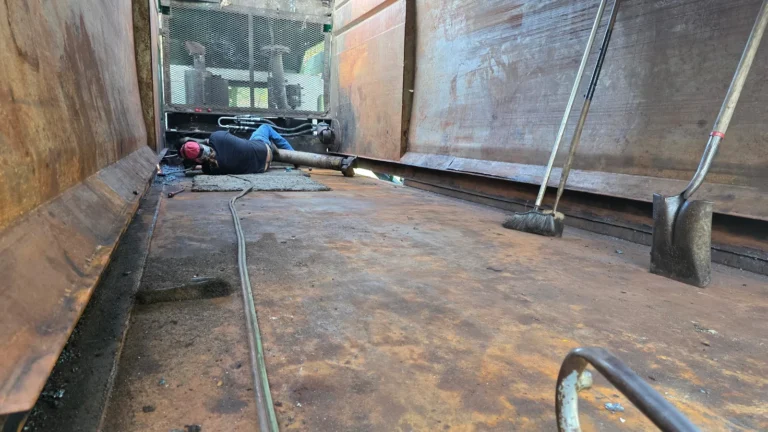 Technician performing floor repair inside a roll-off container at North Florida Container & Truck Repair in Ocala